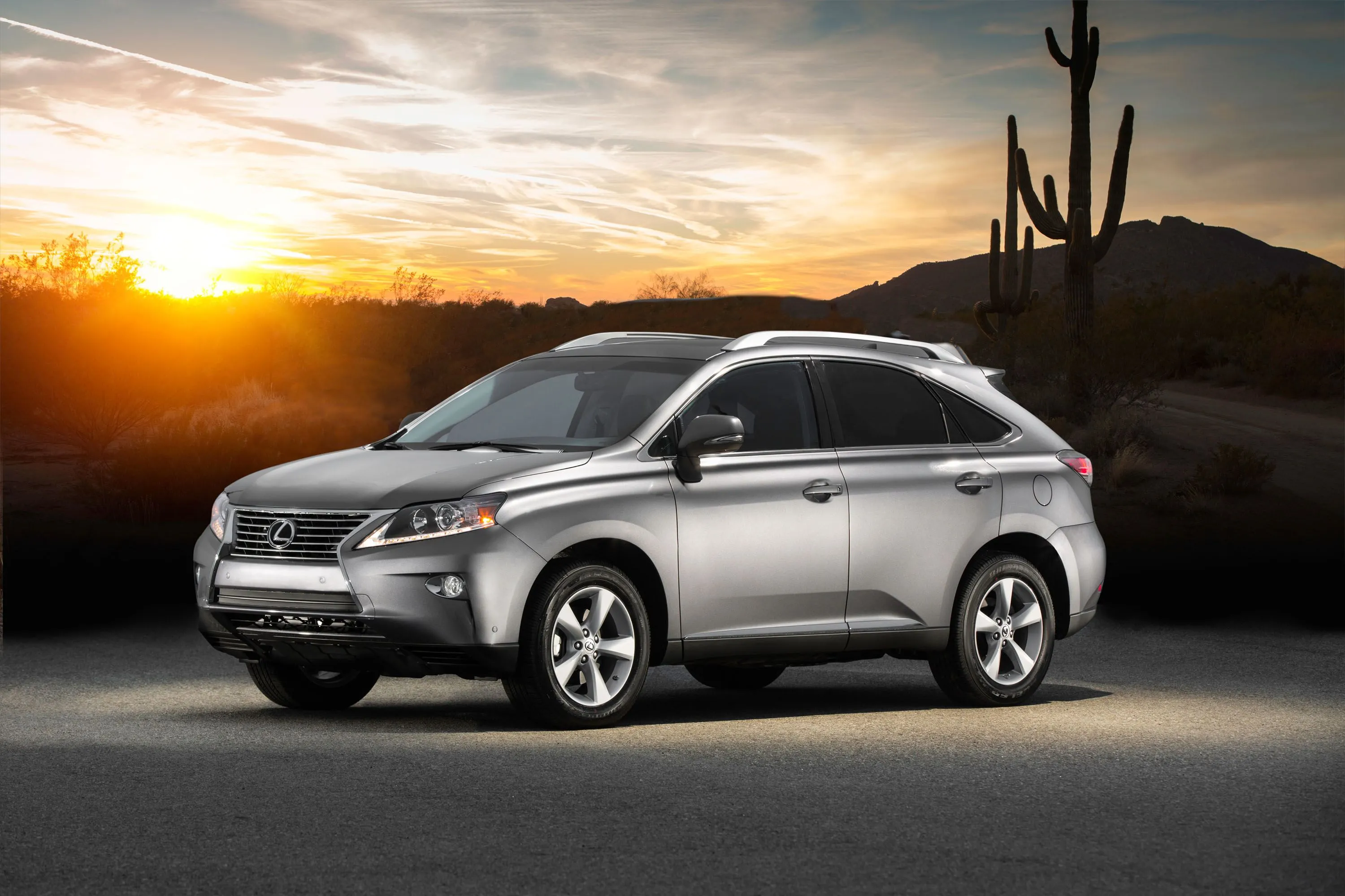 Lexus RX 350 2015 màu bạc đang đỗ với phong cảnh sa mạc hoàng hôn phía sau, thể hiện sự sang trọng của mẫu SUV đáng tin cậy.