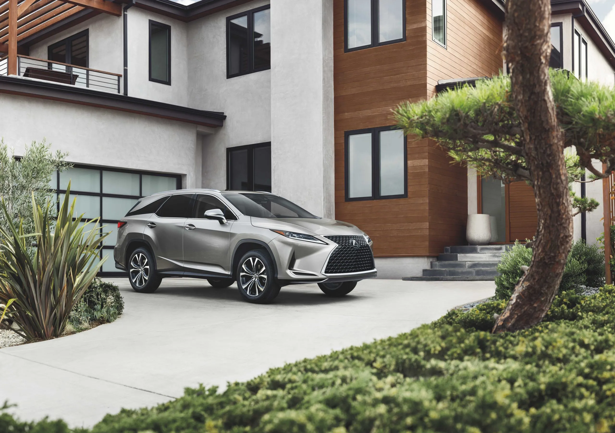 Lexus RX 350L 2022 màu bạc đỗ trên lối vào nhà, thể hiện sự thoải mái và các tính năng an toàn cao cấp của dòng SUV 3 hàng ghế.