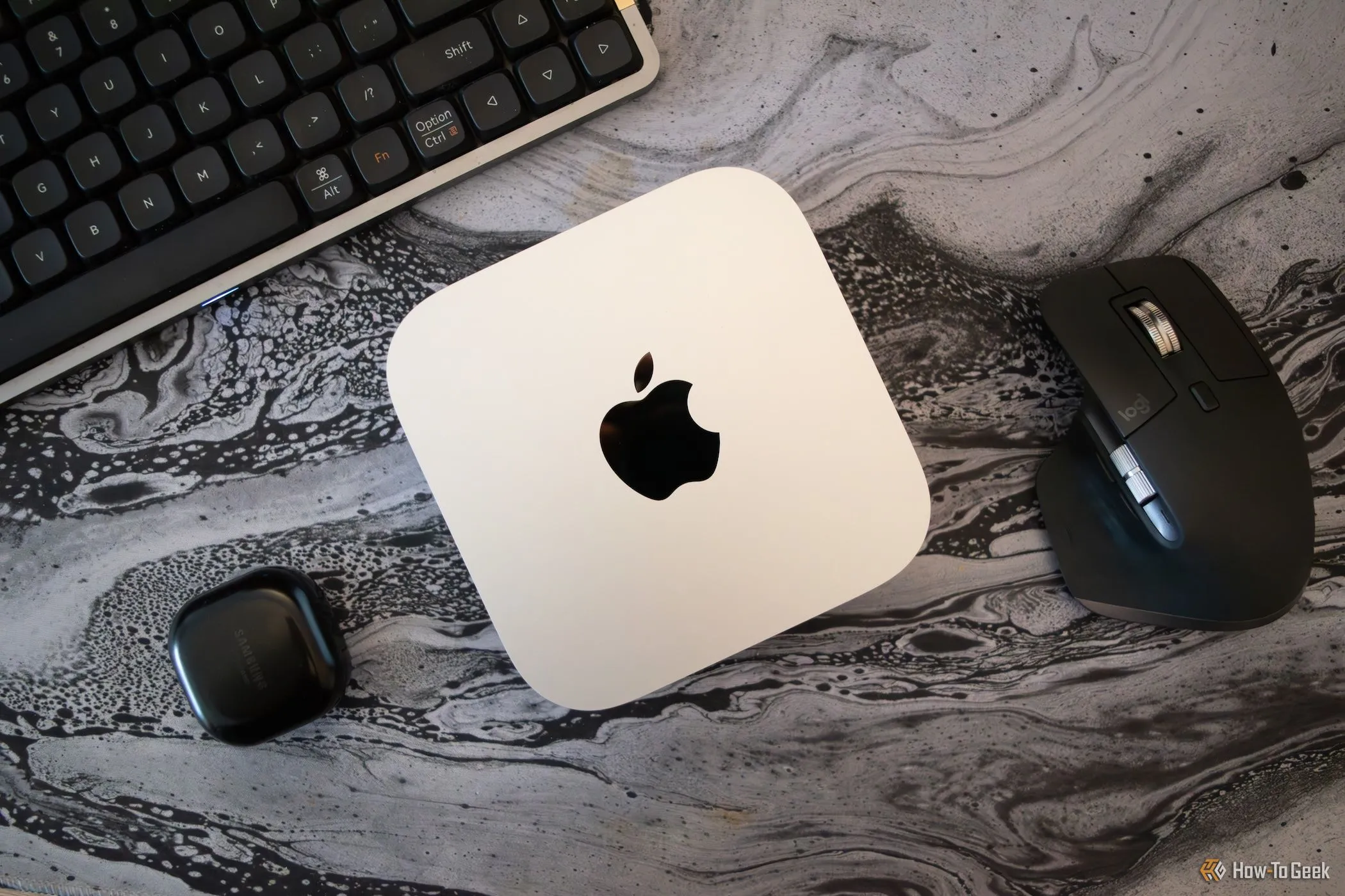 Mac Mini M4 trên bàn làm việc cùng với màn hình, bàn phím, chuột và các thiết bị ngoại vi khác, thể hiện không gian làm việc gọn gàng.