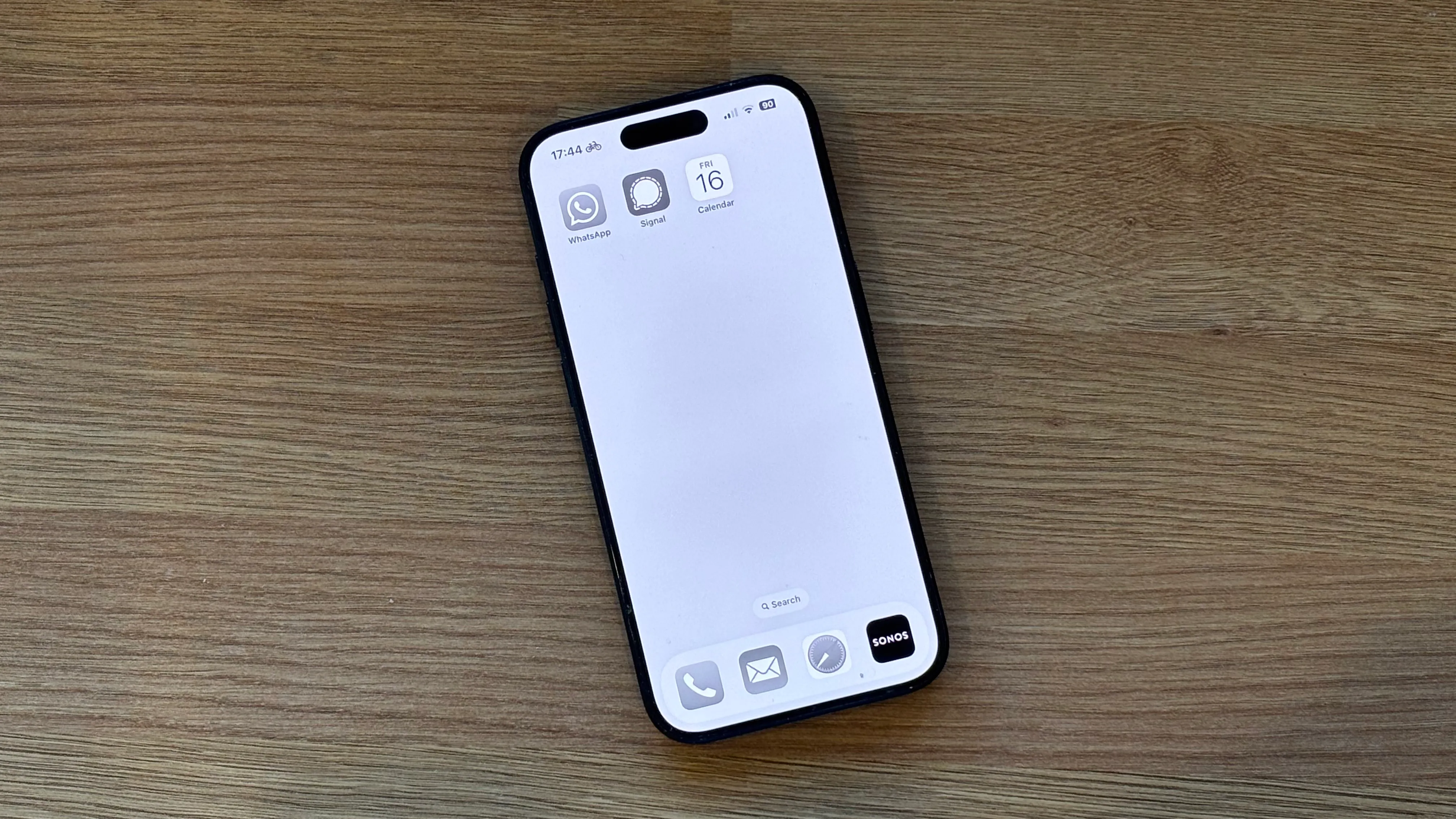 Màn hình chính iPhone ở chế độ thang độ xám (Grayscale Mode) với chỉ ba ứng dụng, minh họa cách làm giảm sự hấp dẫn của điện thoại.