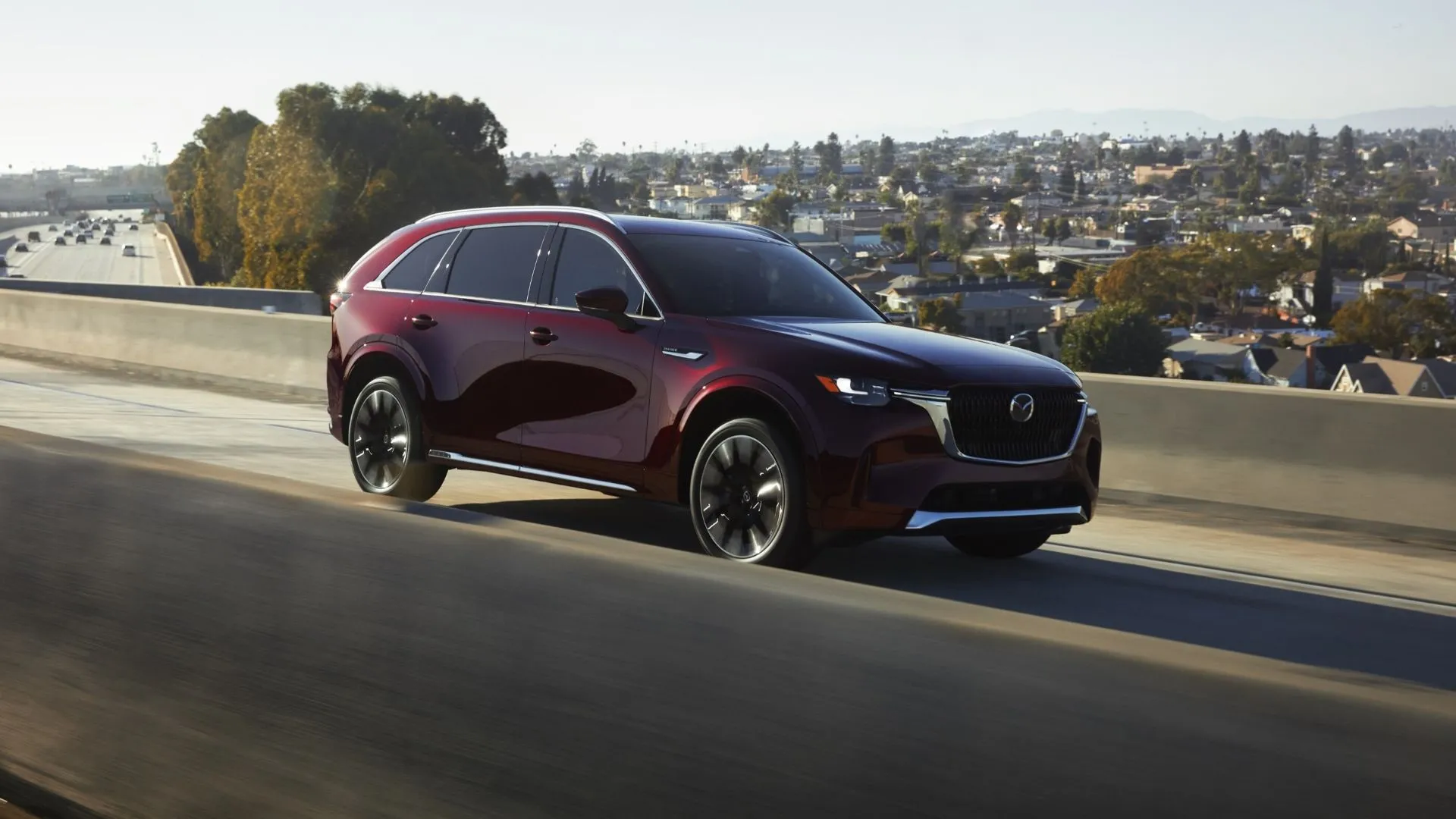 Mazda CX-90 2025 màu đỏ đặc trưng của Mazda đang di chuyển, nổi bật với thiết kế thanh lịch và hiện đại của SUV cỡ trung