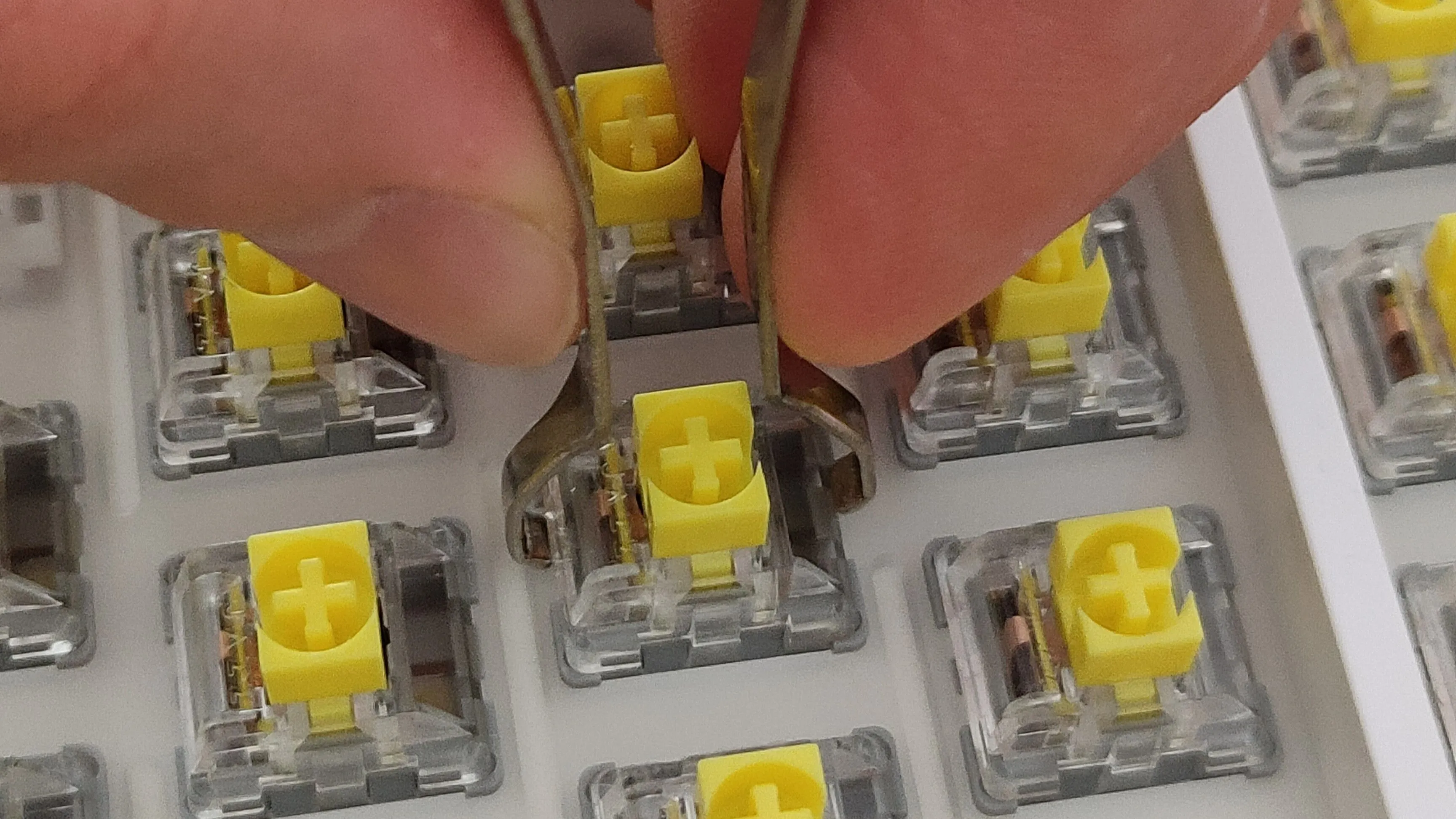 Một bàn tay đang dùng dụng cụ chuyên dụng để tháo switch bàn phím cơ, minh họa khả năng thay thế linh hoạt
