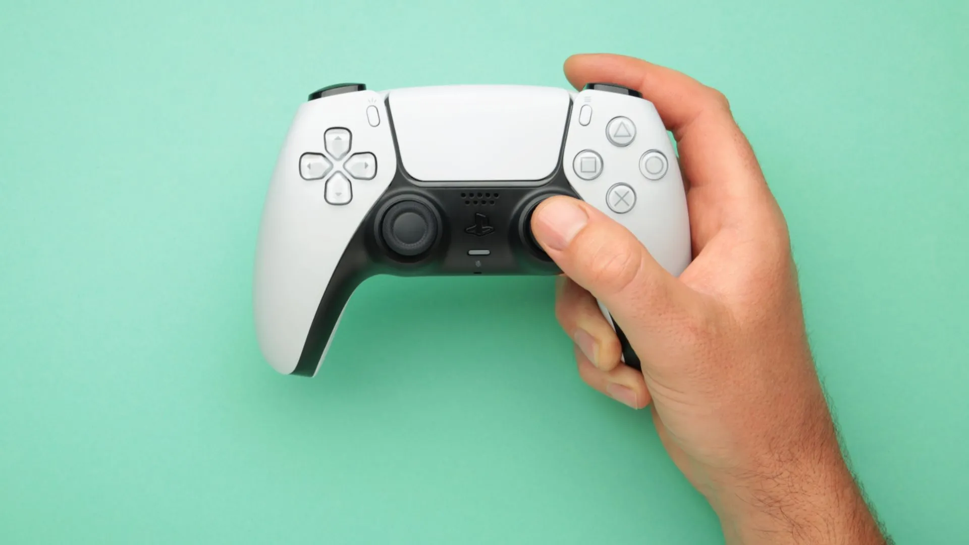 Người đàn ông cầm tay cầm không dây DualSense của PlayStation 5, có nút tắt tiếng micro
