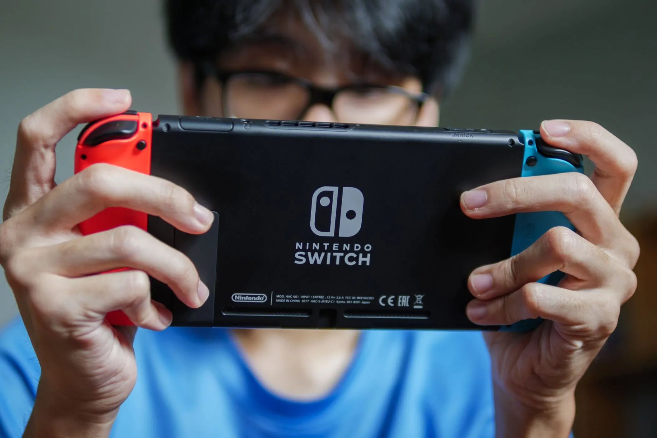 Người đàn ông đang chơi game trên Nintendo Switch ở chế độ cầm tay, minh họa sự tiện lợi của chơi game di động.