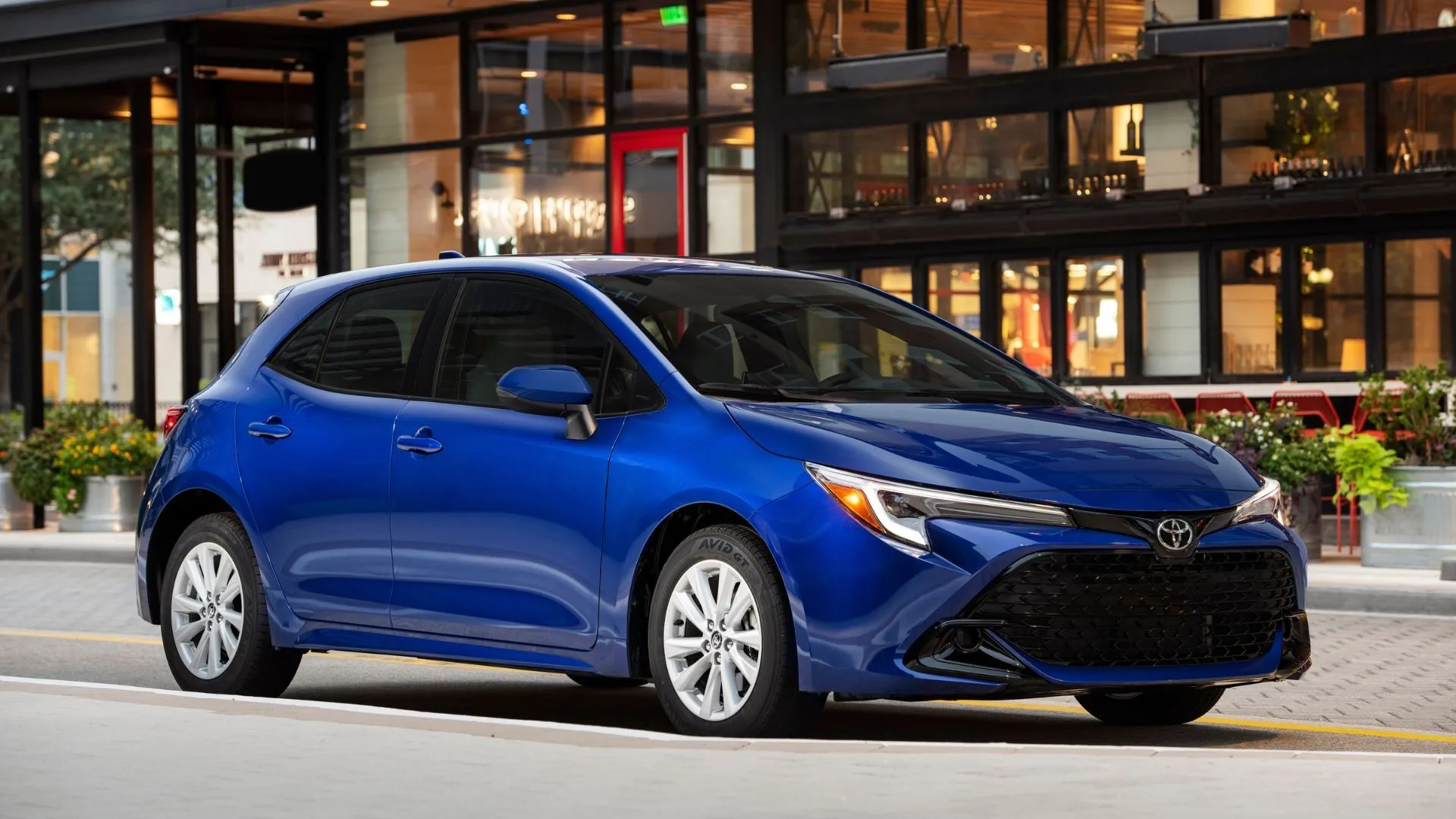 Phần mặt trước 3/4 của xe Toyota Corolla Hatchback SE 2025 màu xanh lam đậu trong thành phố
