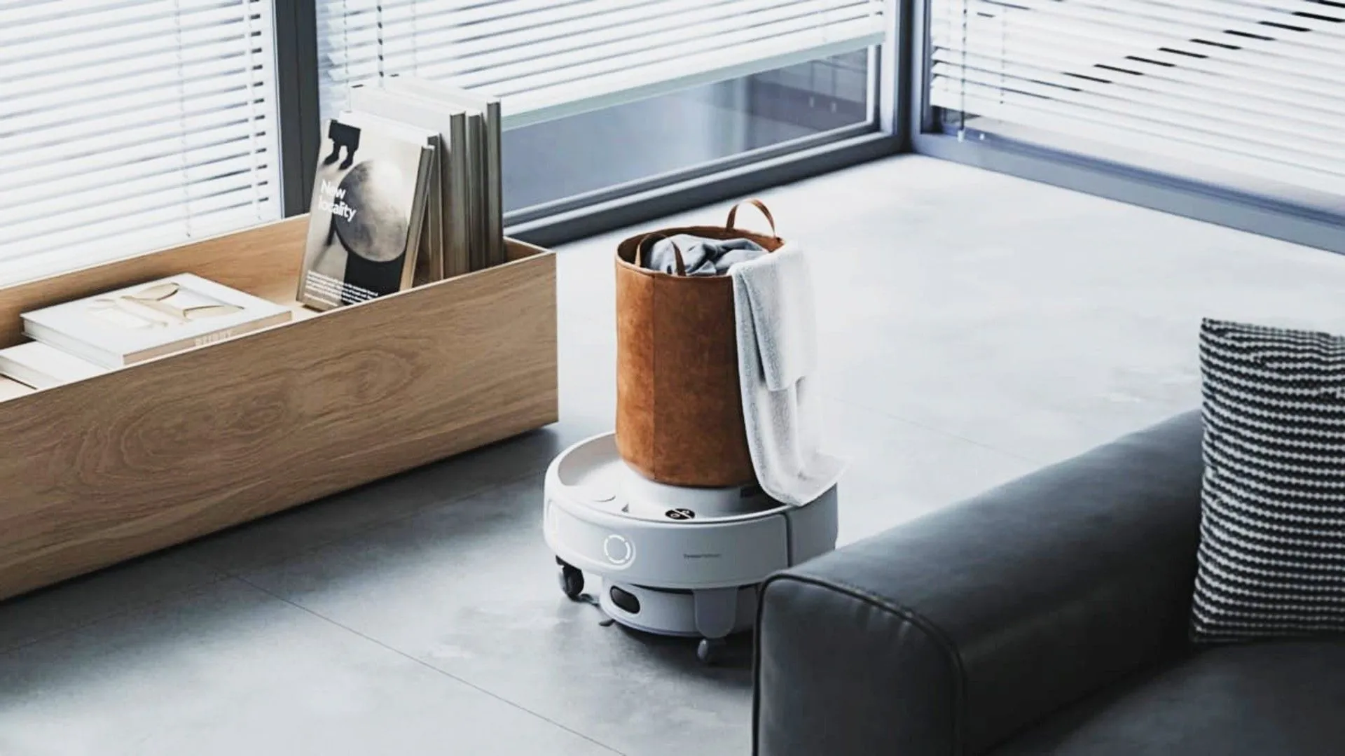 Robot hút bụi SwitchBot hoạt động trên sàn nhà cạnh một túi khăn tắm