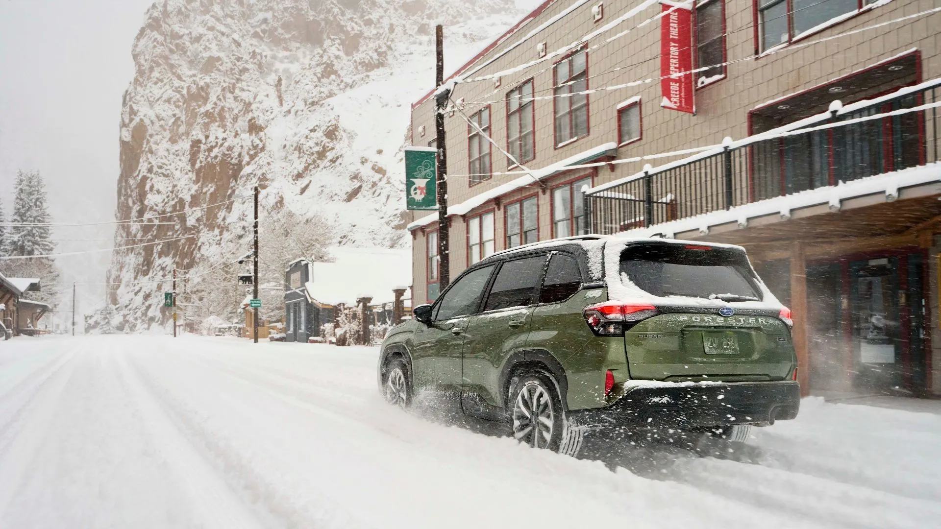 Subaru Forester Hybrid 2025 màu xanh lá cây đang lái trên đường tuyết ở thành phố