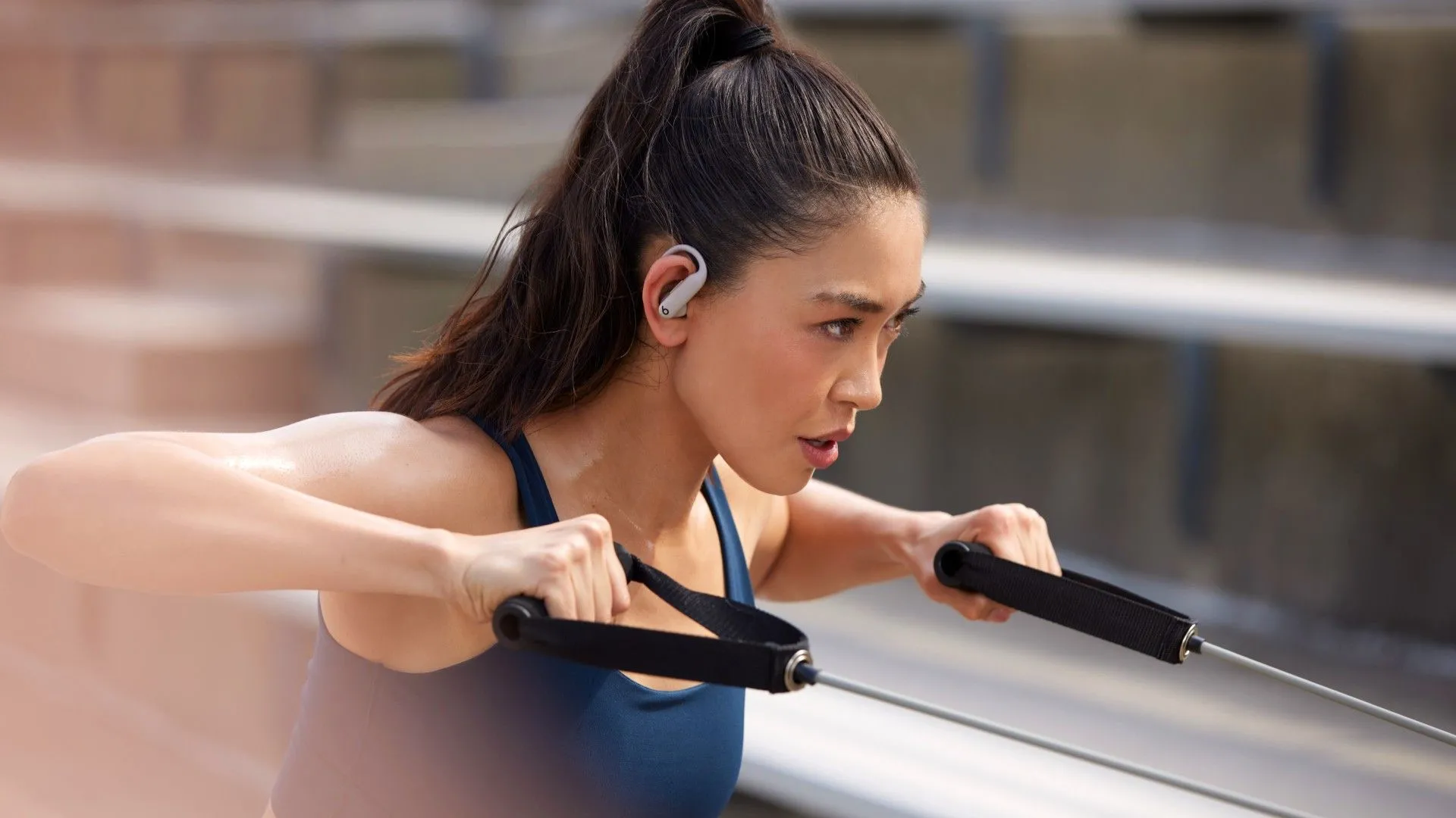 Tai nghe Powerbeats Pro 2 màu đen đang nằm trong tai của một phụ nữ đang tập thể dục