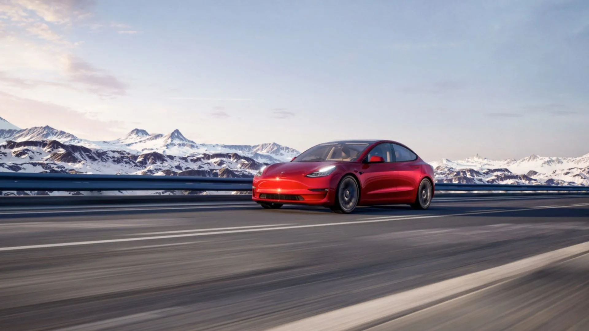 Tesla Model 3 màu đỏ đang di chuyển trên con đường nông thôn với núi tuyết ở phía xa, thể hiện khả năng vượt địa hình và tính năng vận hành của xe.