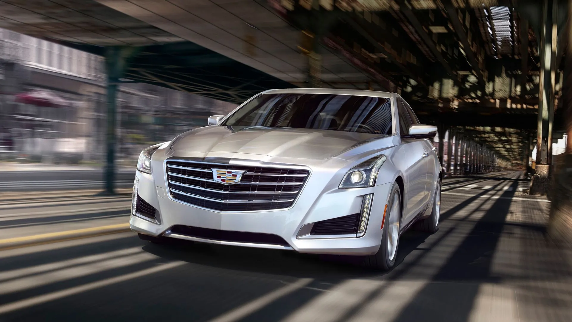 Thiết kế động, góc 3/4 phía trước của chiếc Cadillac CTS 2019 màu bạc đang lái dưới cầu.