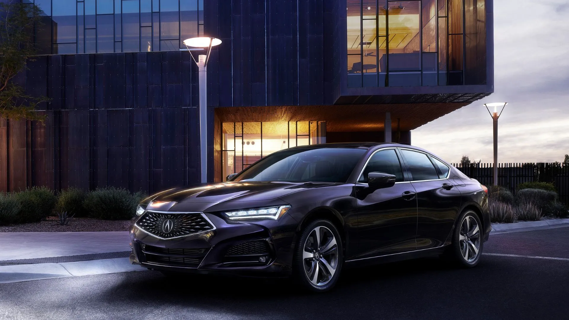 Thiết kế tĩnh, góc 3/4 phía trước của chiếc Acura TLX Advance 2021 màu xanh đậm với một tòa nhà phía sau.