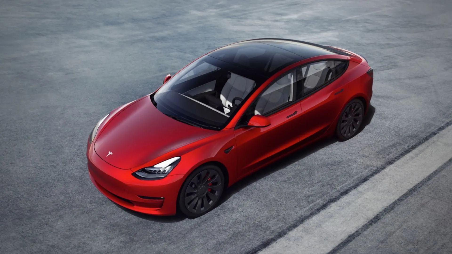 Toàn cảnh chiếc Tesla Model 3 2023 màu đỏ đỗ trên đường nhựa