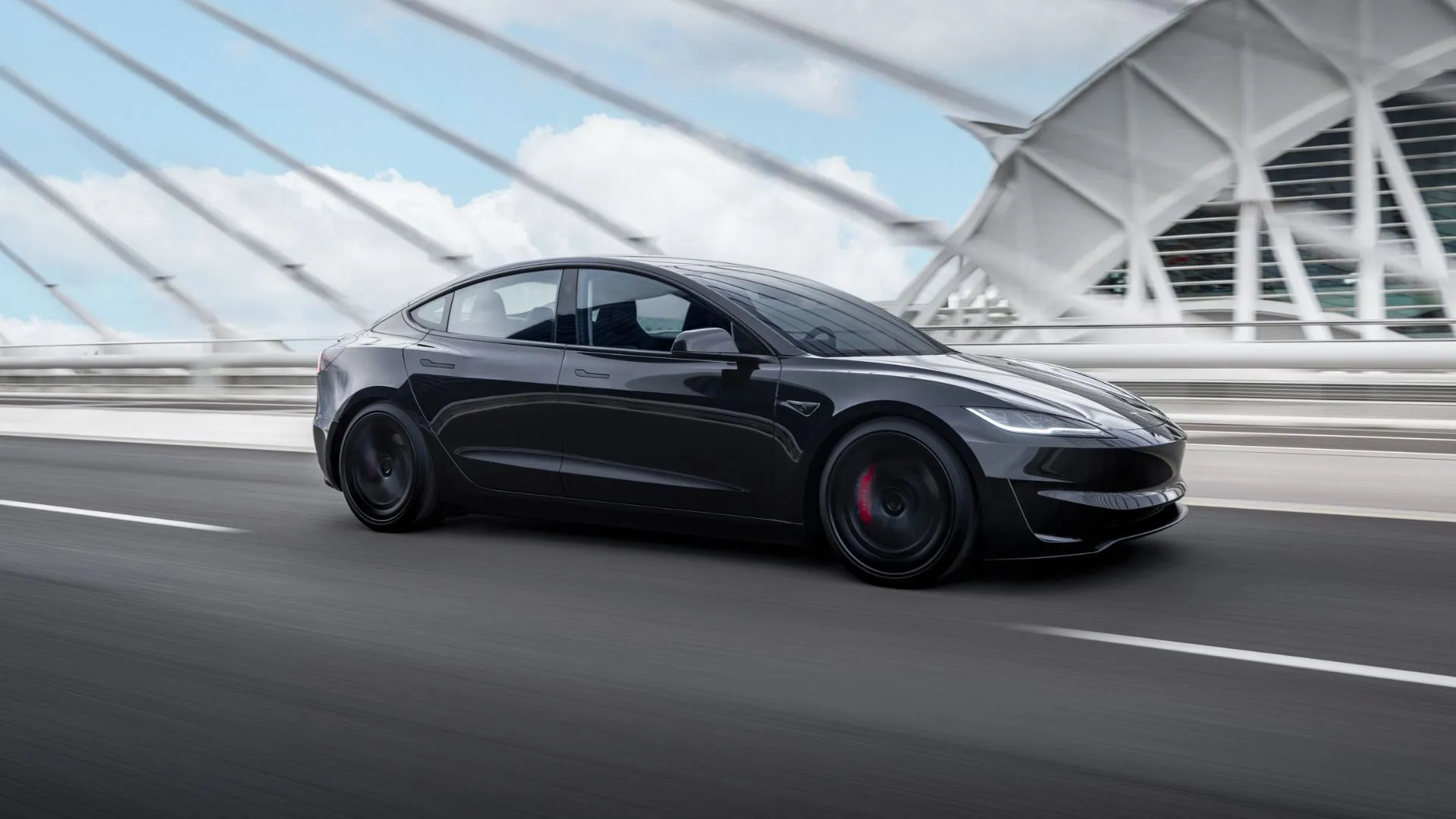 Toàn cảnh chiếc Tesla Model 3 Performance màu đen đang lái qua cầu trong thành phố.
