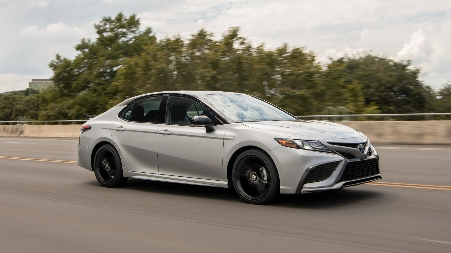 Toyota Camry Hybrid 2022 màu bạc chạy trên đường cao tốc
