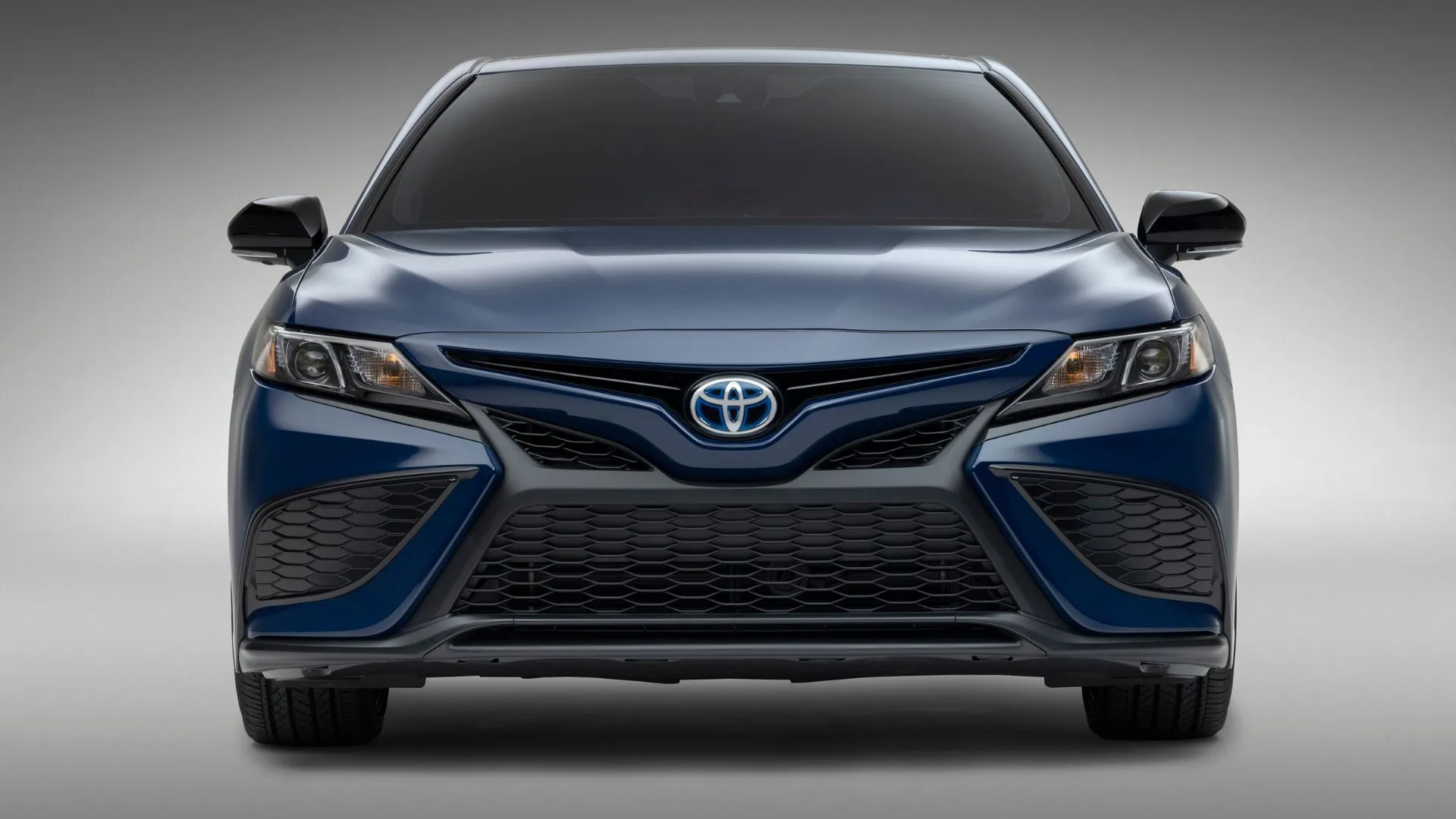 Toyota Camry Hybrid 2023 màu xanh dương chụp tĩnh từ phía trước trong studio với phông nền xám