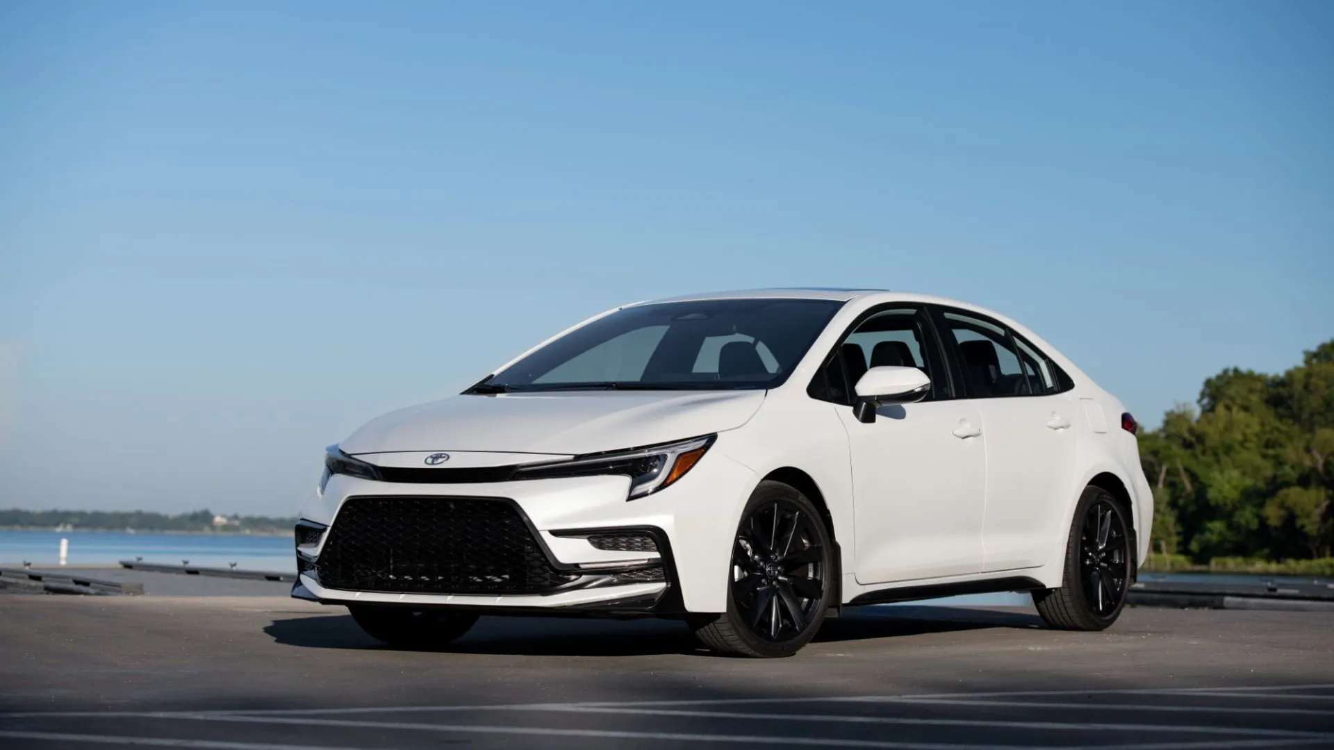 Toyota Corolla Sedan 2025 màu trắng đỗ trước bãi biển