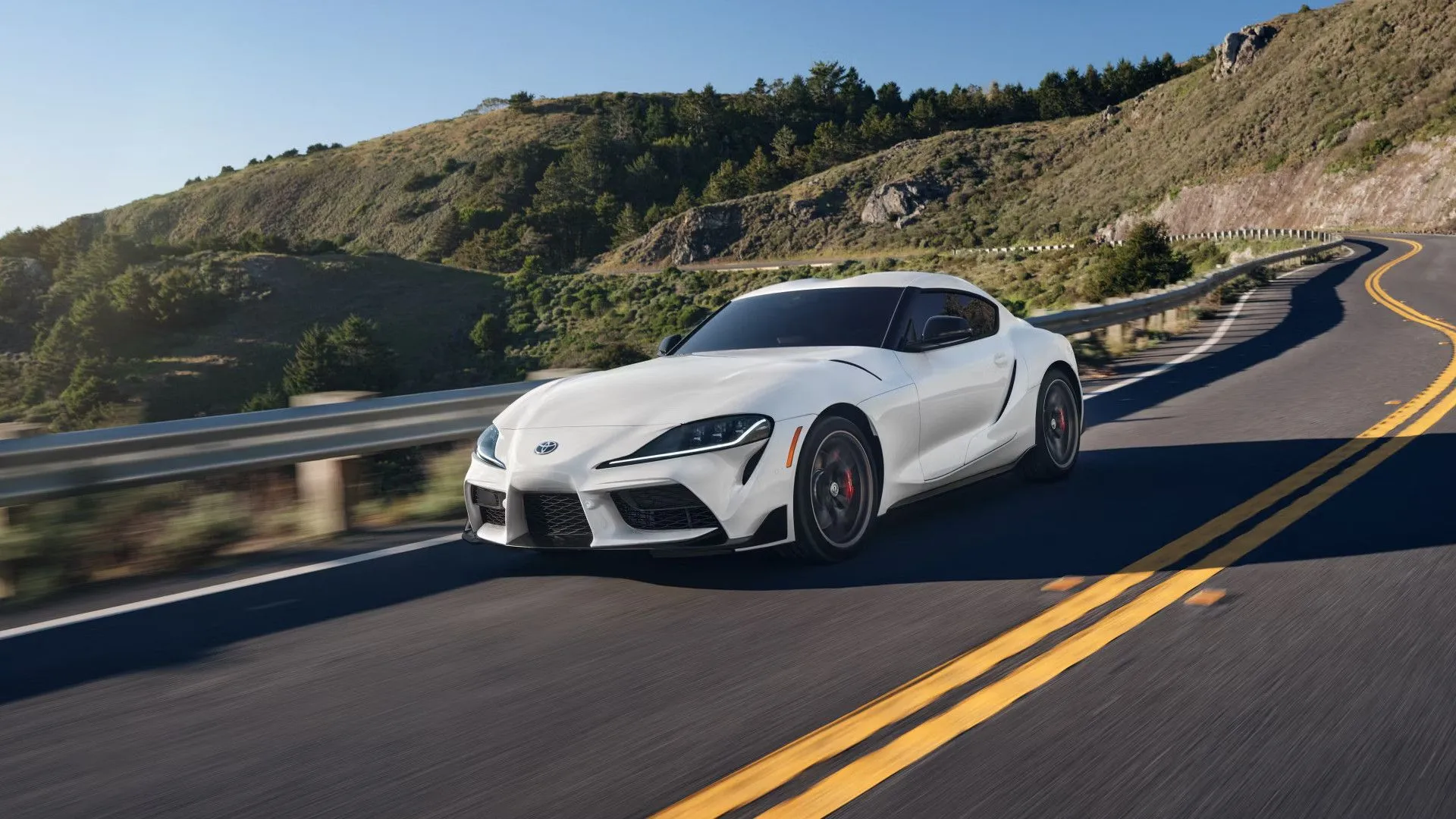 Toyota GR Supra 2025 màu trắng đang lái trên con đường núi quanh co, thể hiện khả năng xử lý linh hoạt