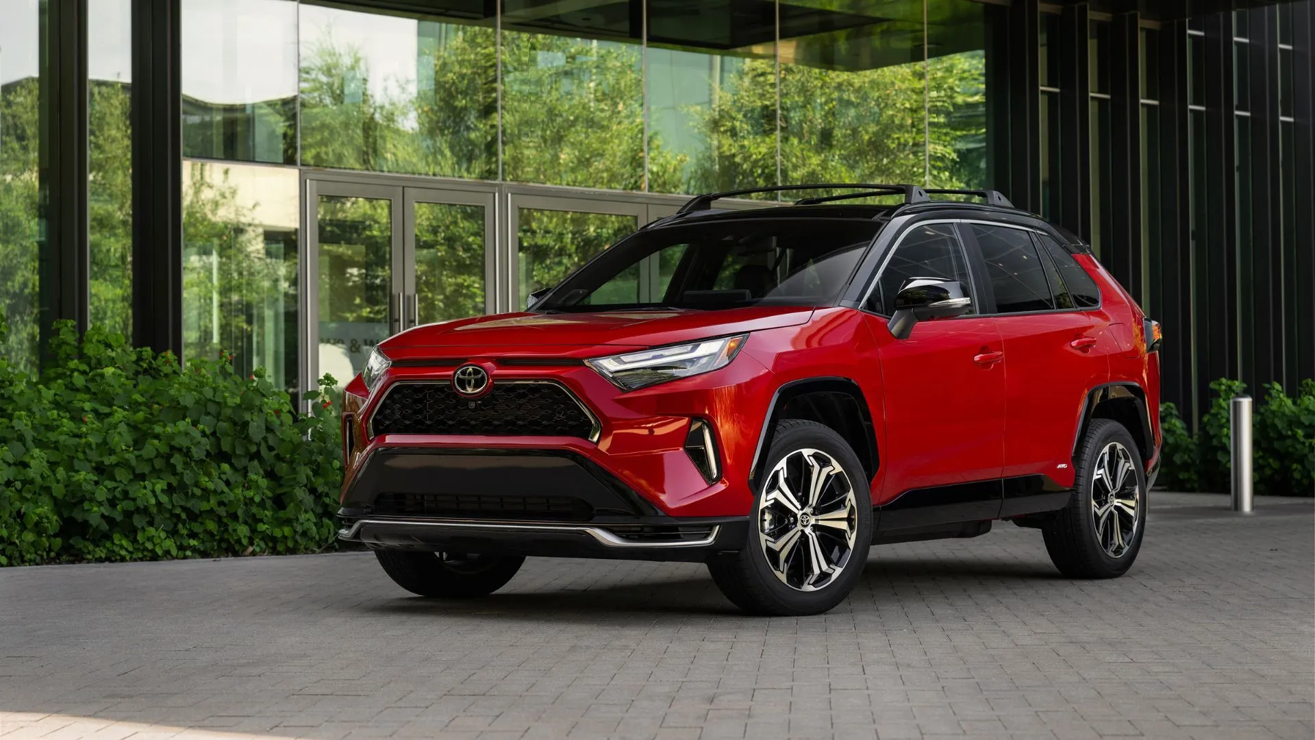 Toyota RAV4 PHEV XSE 2025 màu đỏ đỗ bên ngoài tòa nhà hiện đại, SUV dẫn đầu doanh số