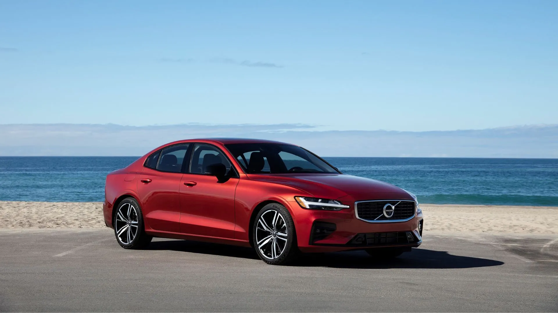 Volvo S60 2025 R-Design màu trắng đỗ bên bãi biển, nổi bật với thiết kế Bắc Âu, an toàn và tích hợp Google.