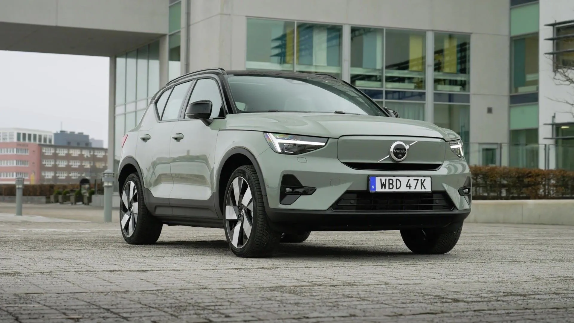 Volvo XC40 Plus B5 AWD 2025 màu xanh lá cây trang nhã đậu trước một tòa nhà, với thiết kế Scandinavian tinh tế