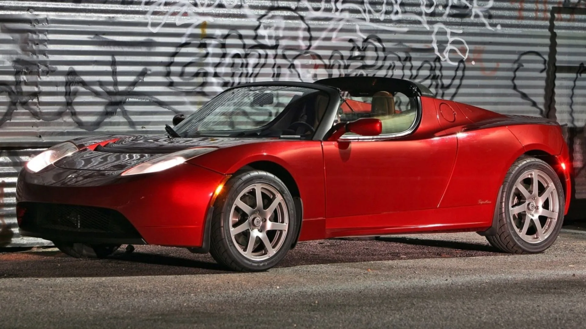 Xe Tesla Roadster thế hệ đầu tiên bên ngoài một bức tường graffiti