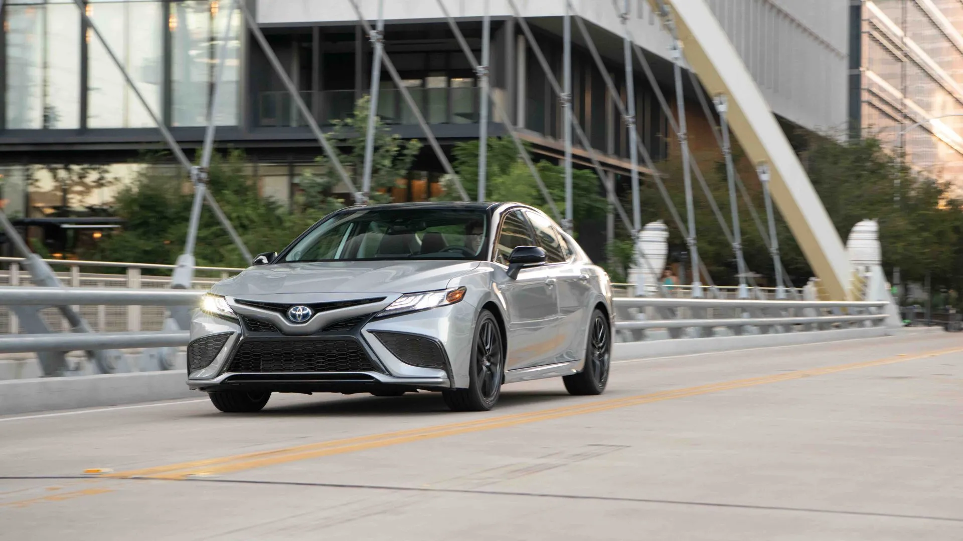 Xe Toyota Camry 2022 Hybrid màu bạc đang chạy trên đường phố
